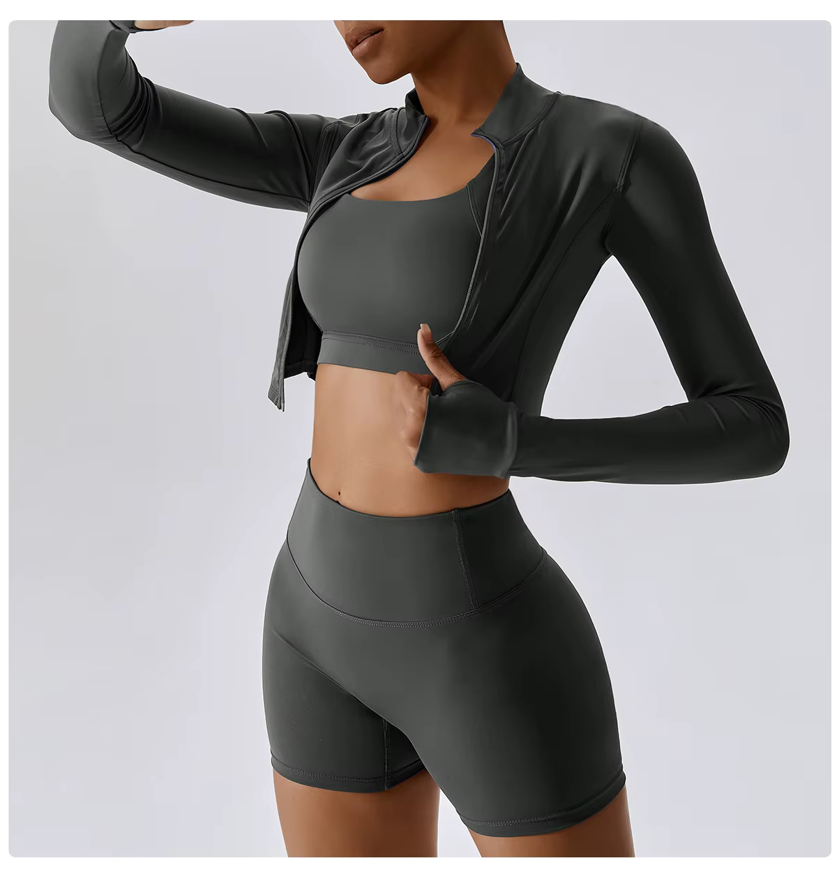 Woman in black athletic wear posing against a light gray background