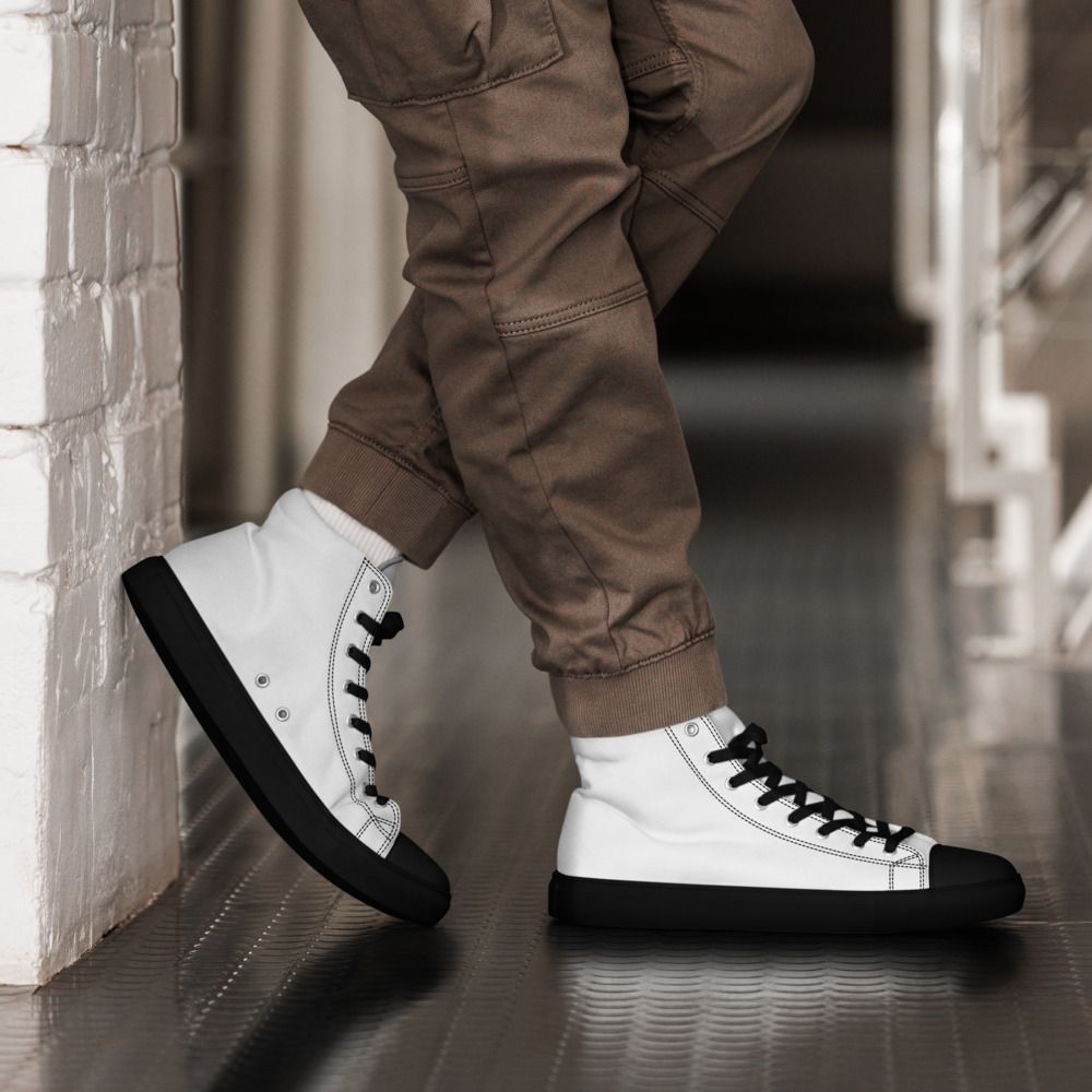White high-top sneaker with black laces, toe cap, sole, and a circular red-and-black patch logo on the ankle
