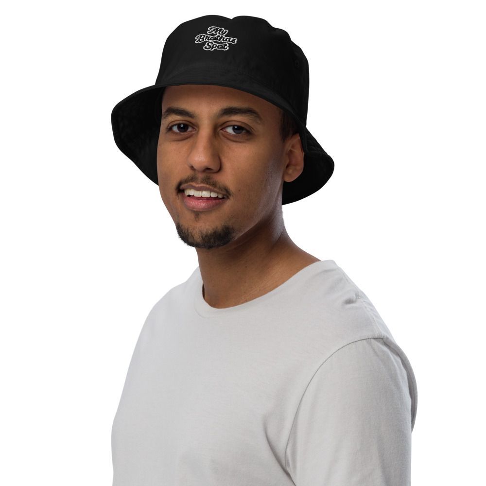 Man in a black bucket hat and white shirt, smiling against a white background