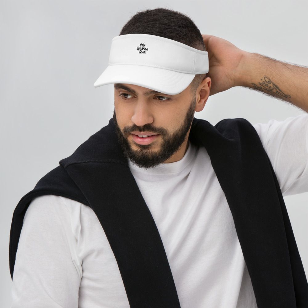 Man wearing a white visor and black jacket, adjusting the back of his head against a gray background