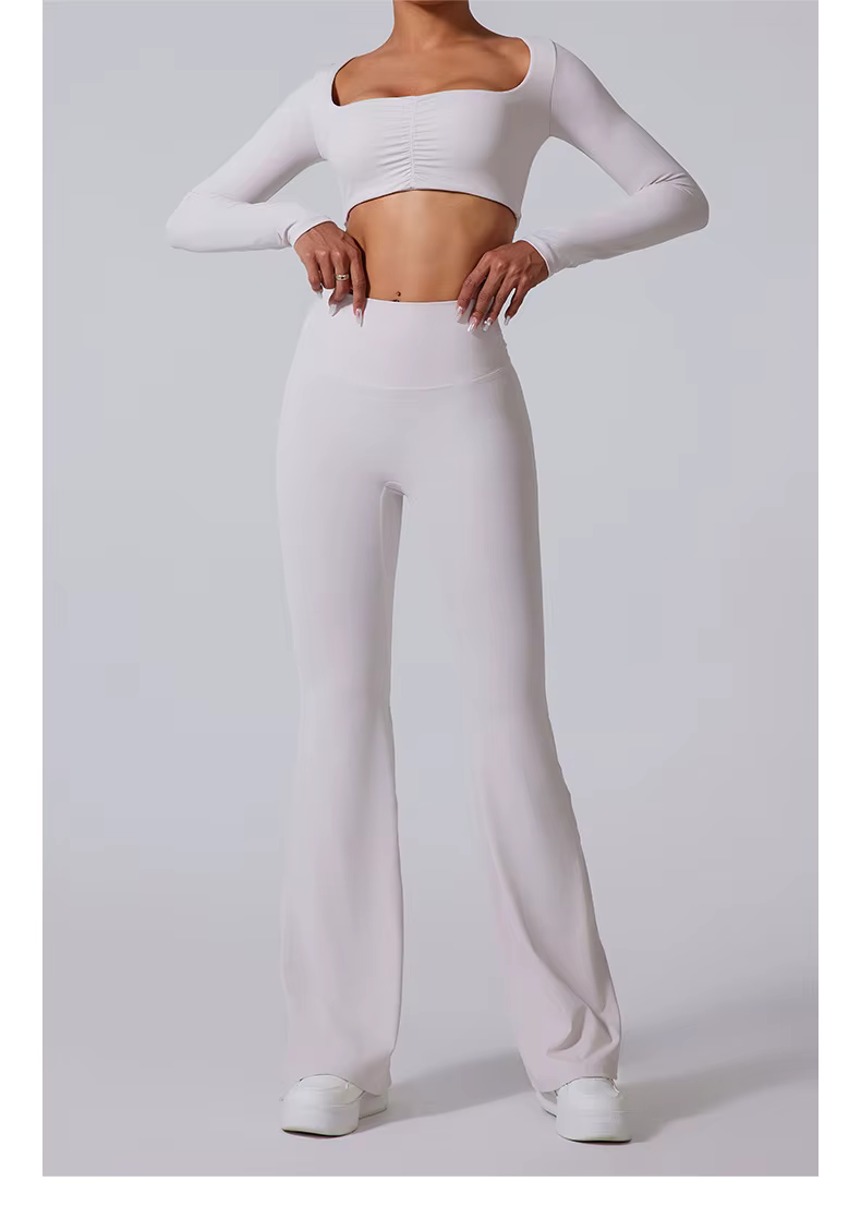 Model wearing black one-shoulder crop top and high-waisted flared pants, standing against a gray backdrop
