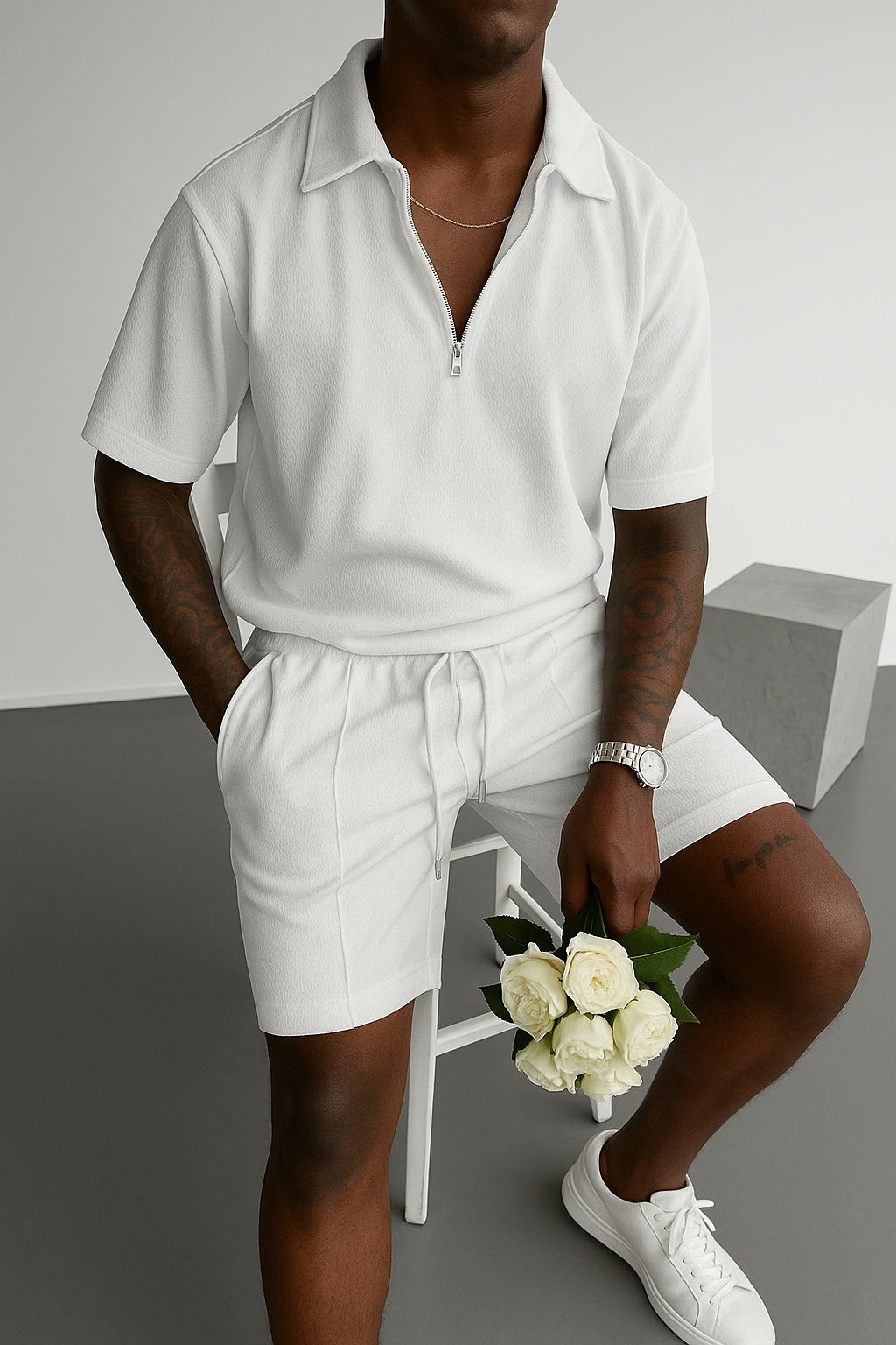 Person seated on a chair wearing a white outfit and holding a small bouquet of flowers.