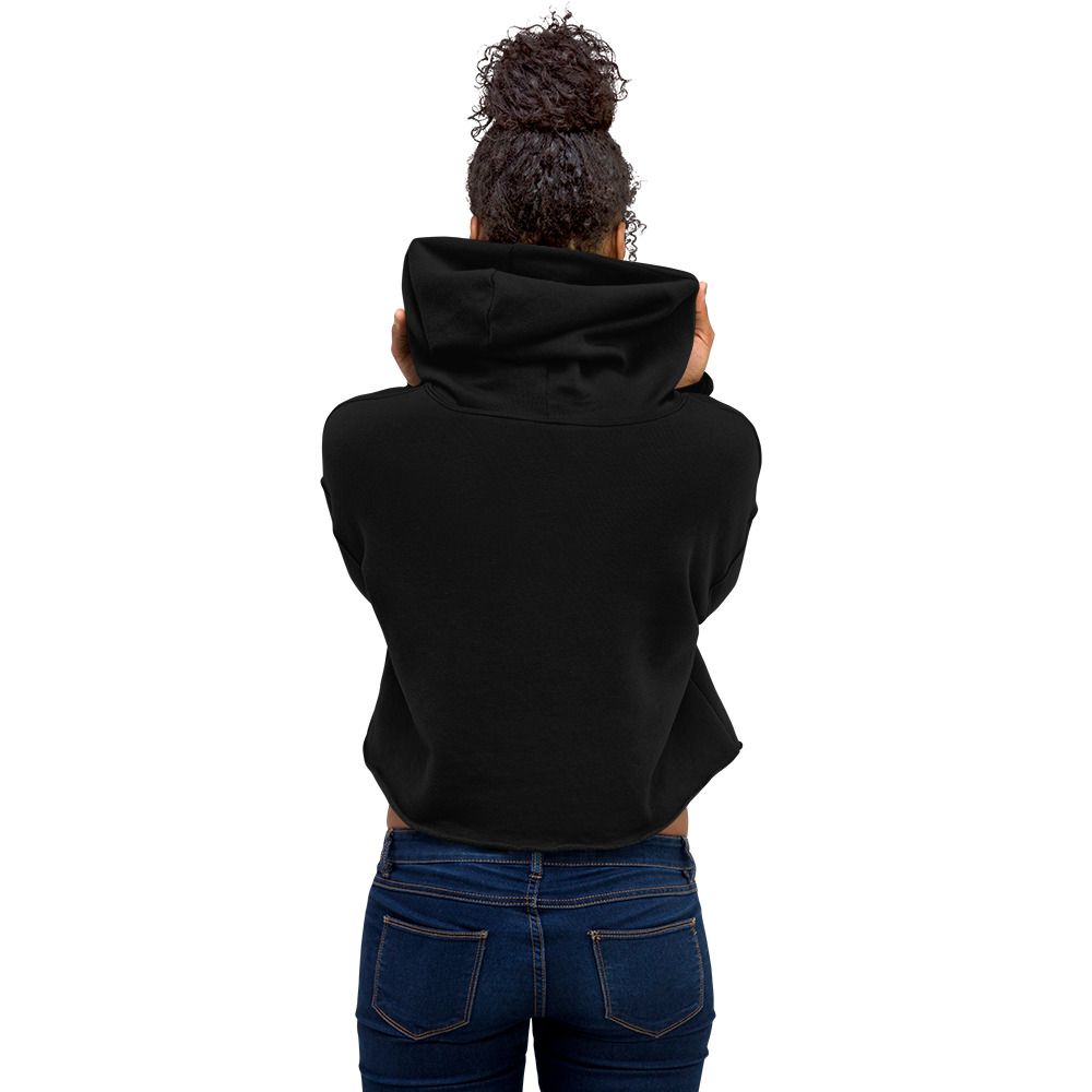 Person in a black hoodie and dark leggings posing against a beige wall, looking to the side.