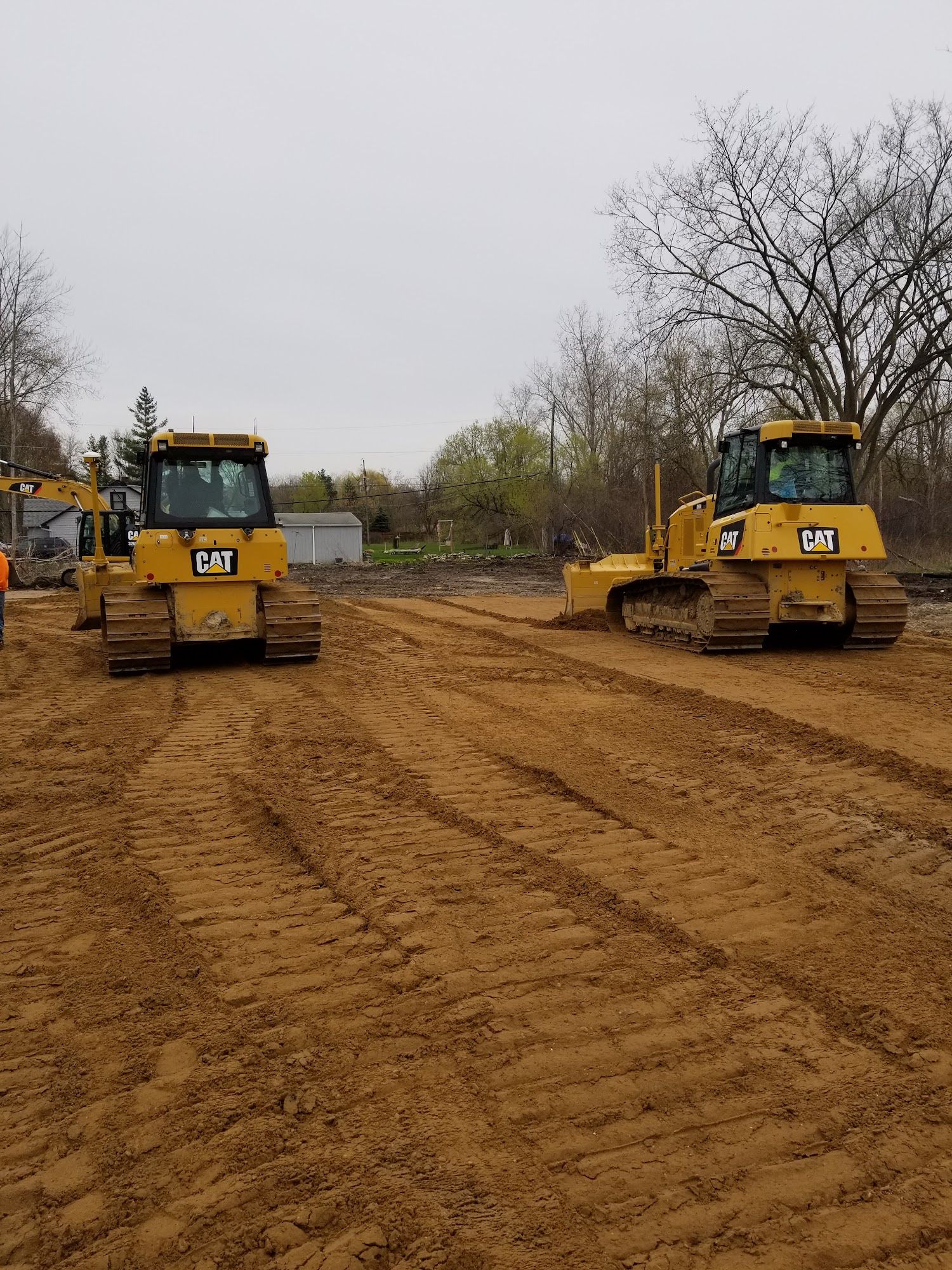 Two yellow Caterpillar bulldozers on a dirt lot, preparing a construction site.