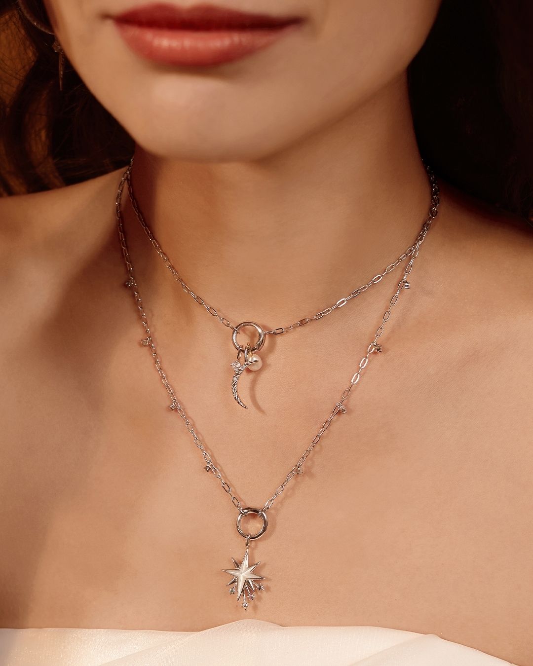 Femme portant des colliers en argent superposés : pendentifs en forme de croissant de lune et d'étoile.