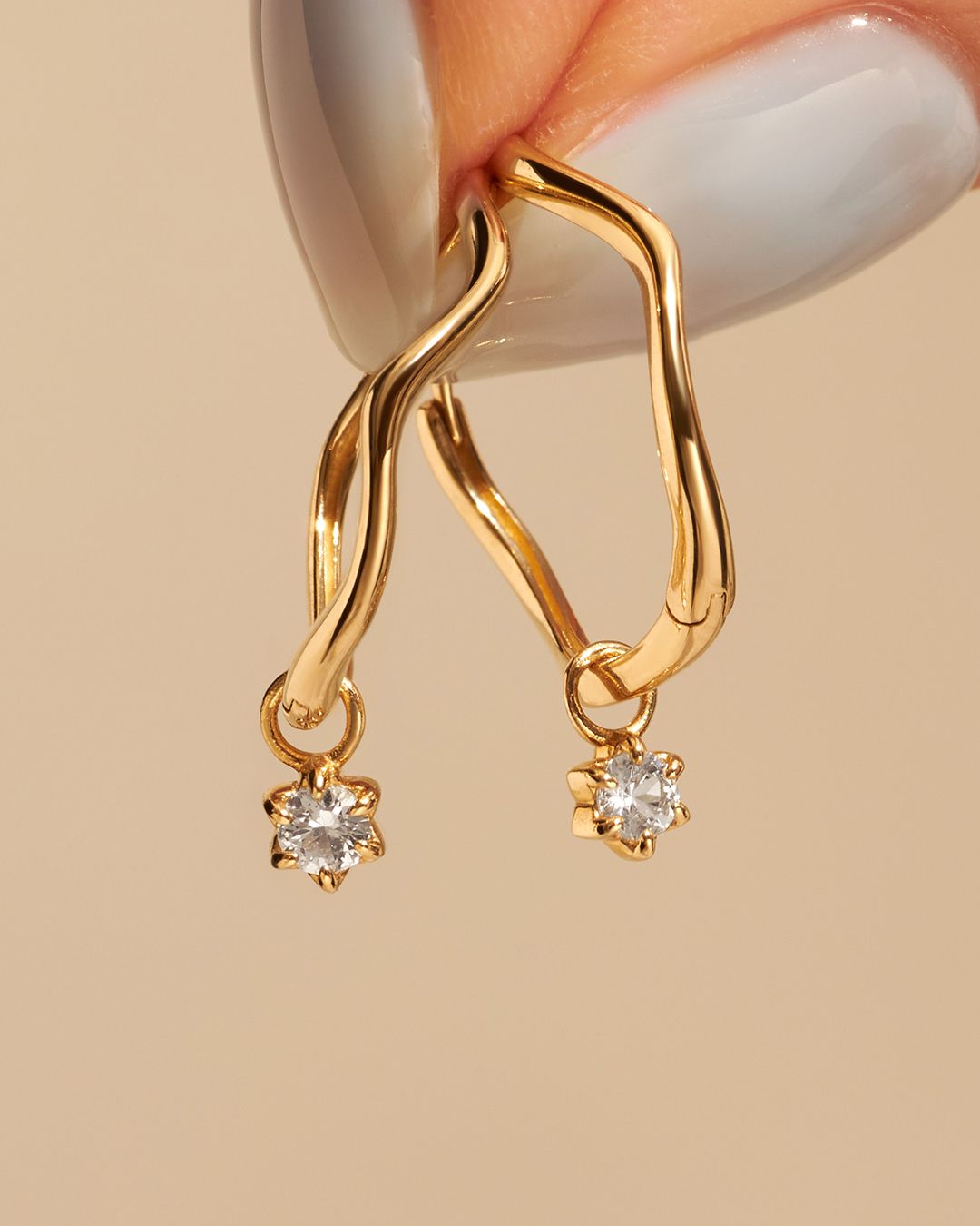 Boucles d'oreilles créoles en or avec accents de diamants pendants.