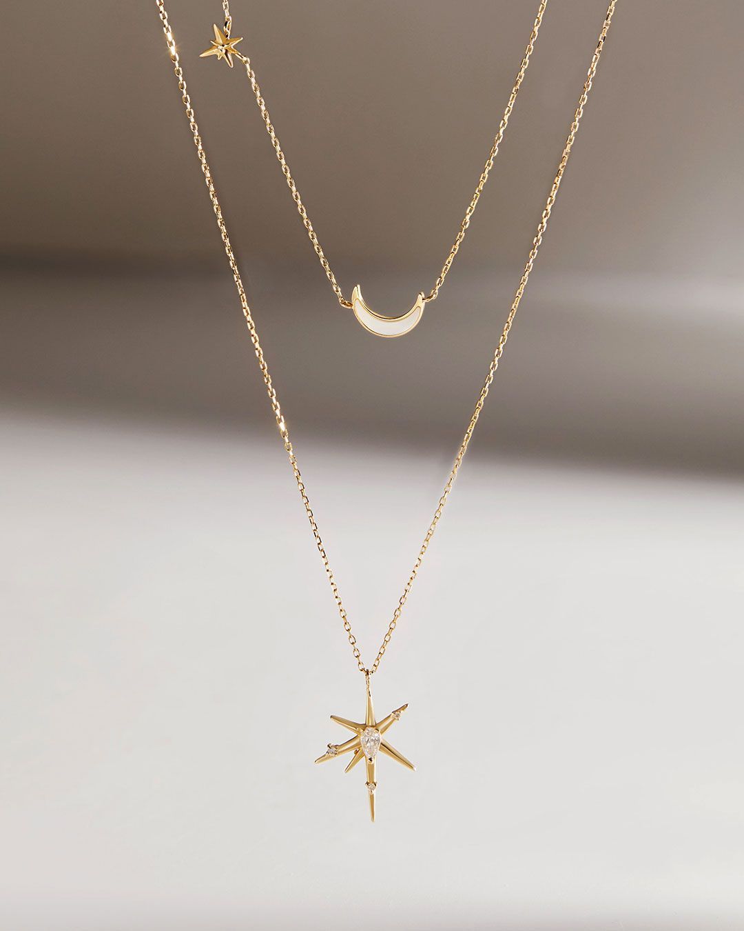 Collier en or superposé avec un pendentif en forme d'étoile, de croissant de lune et d'étoile.