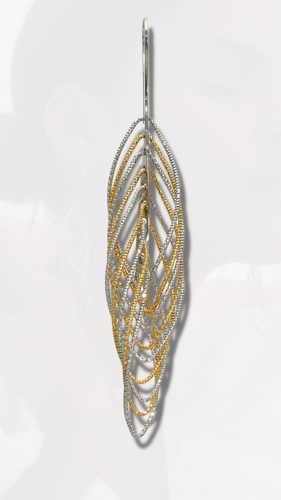Boucle d'oreille pendante en forme de feuille ; design en filigrane argent et or ; fond blanc.