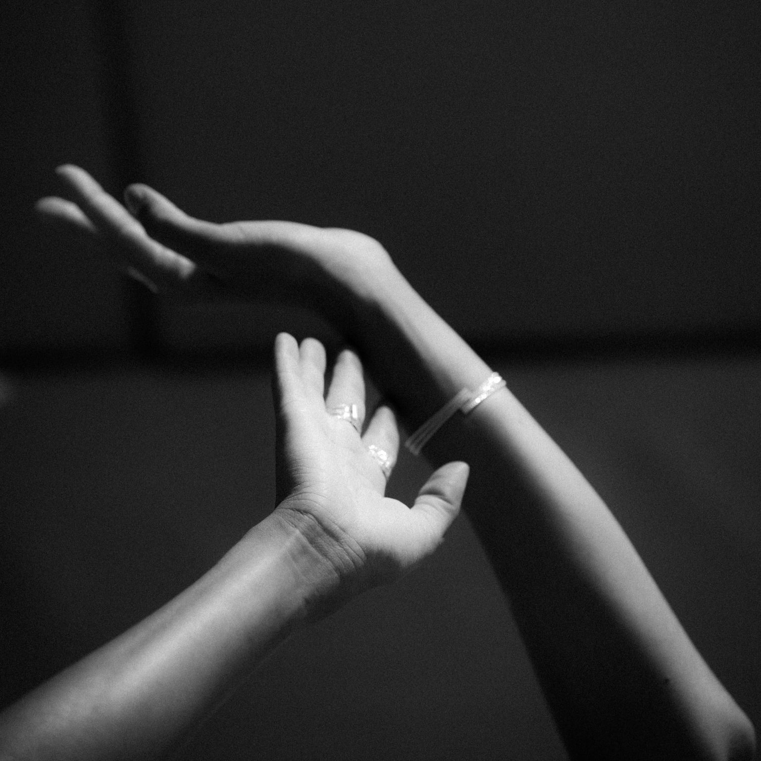 Deux mains se tendent, l'une sur l'autre. Une main est tournée vers le haut, l'autre tendue vers le haut. Noir et blanc.