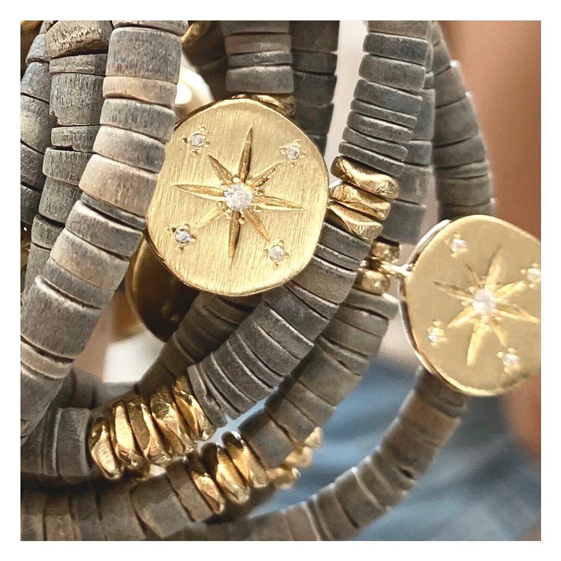 Pile de bracelets en perles grises et dorées avec des breloques en forme d'étoile.
