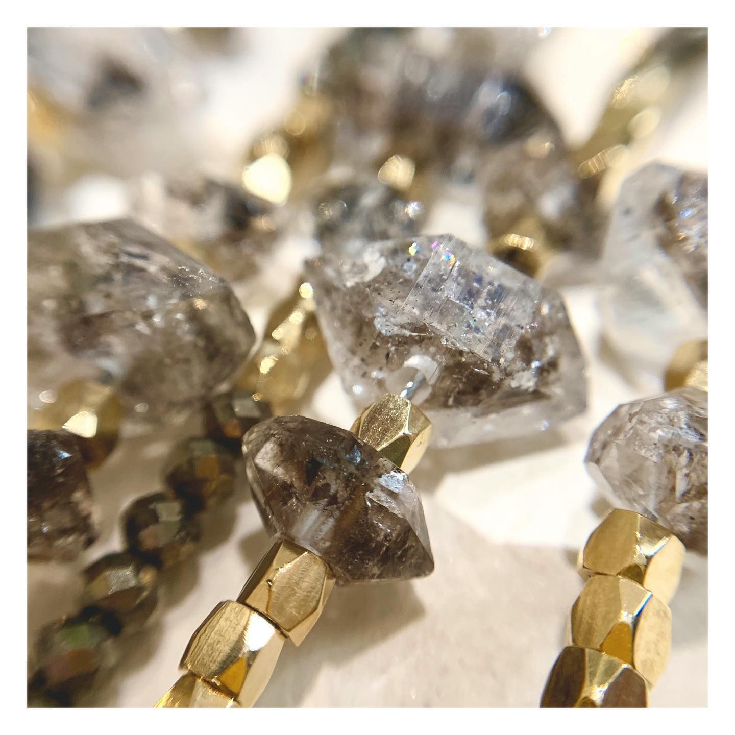 Gros plan d'un collier de pierres précieuses avec du quartz fumé taillé grossièrement et des perles d'or.