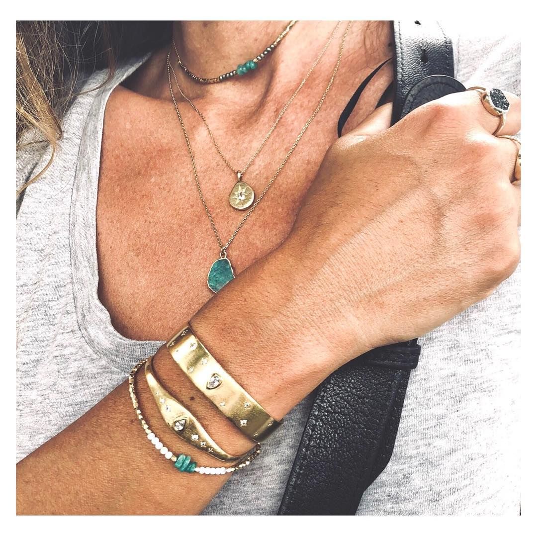 Femme portant plusieurs colliers, bracelets et bagues en or.