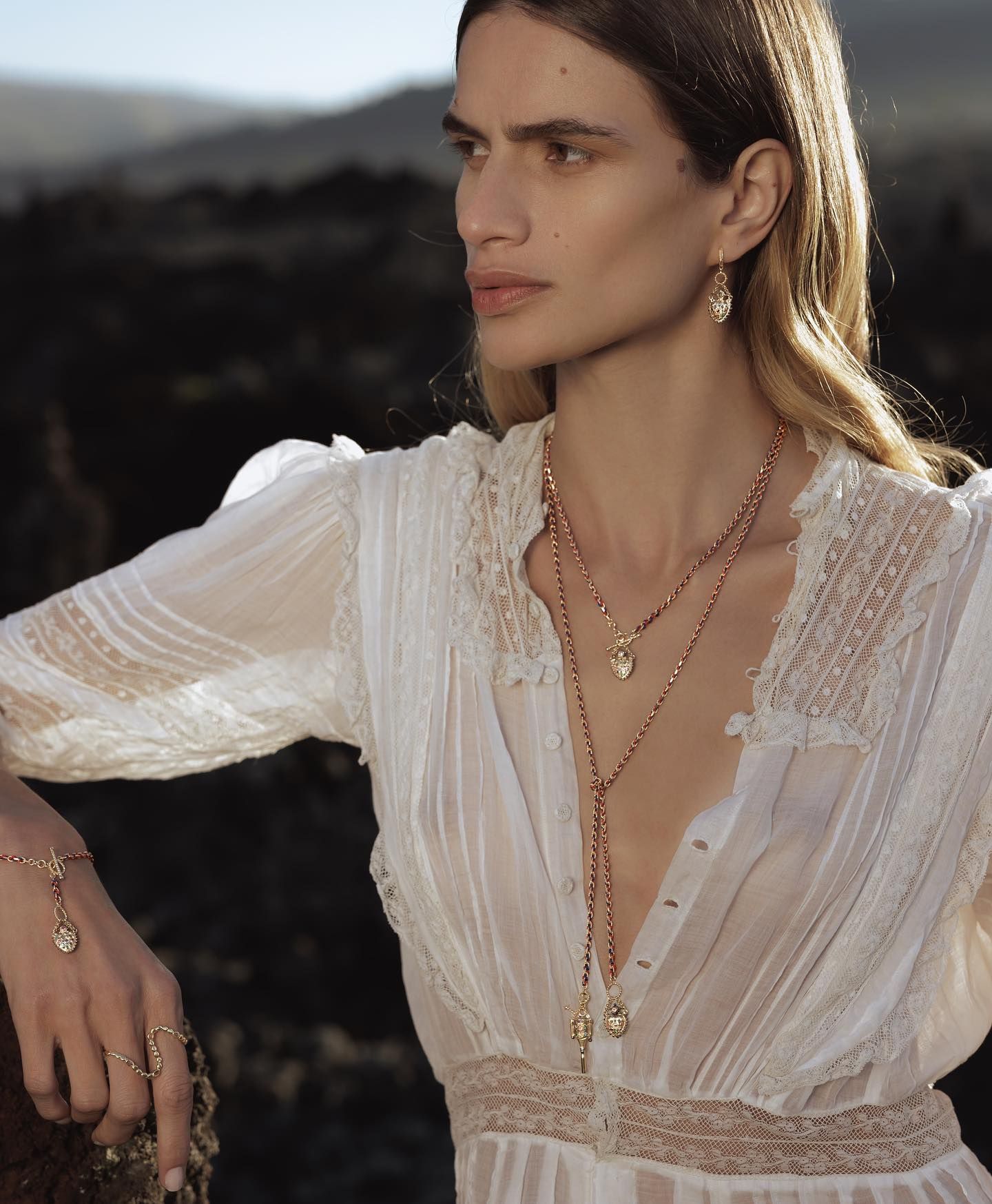 Femme portant des bijoux, robe blanche, à l'extérieur.
