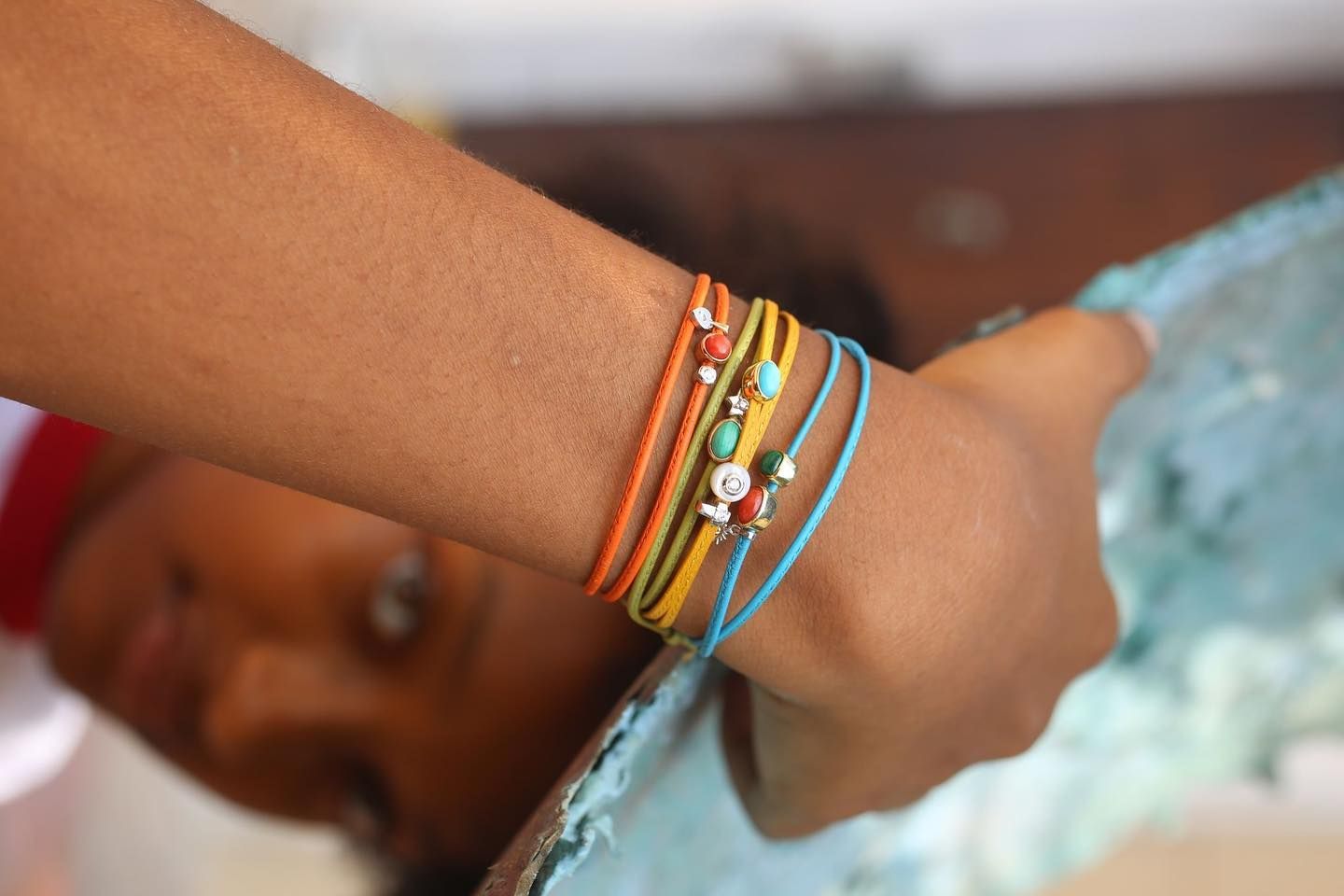 Bras d'une personne portant plusieurs bracelets colorés, tenant un objet bleu.