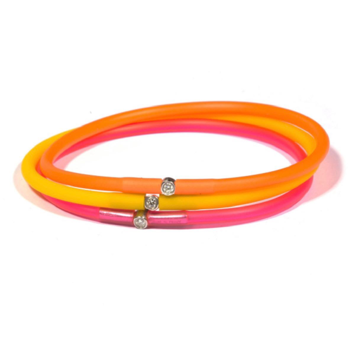 Trois bracelets en caoutchouc colorés avec de petits accents argentés, empilés.