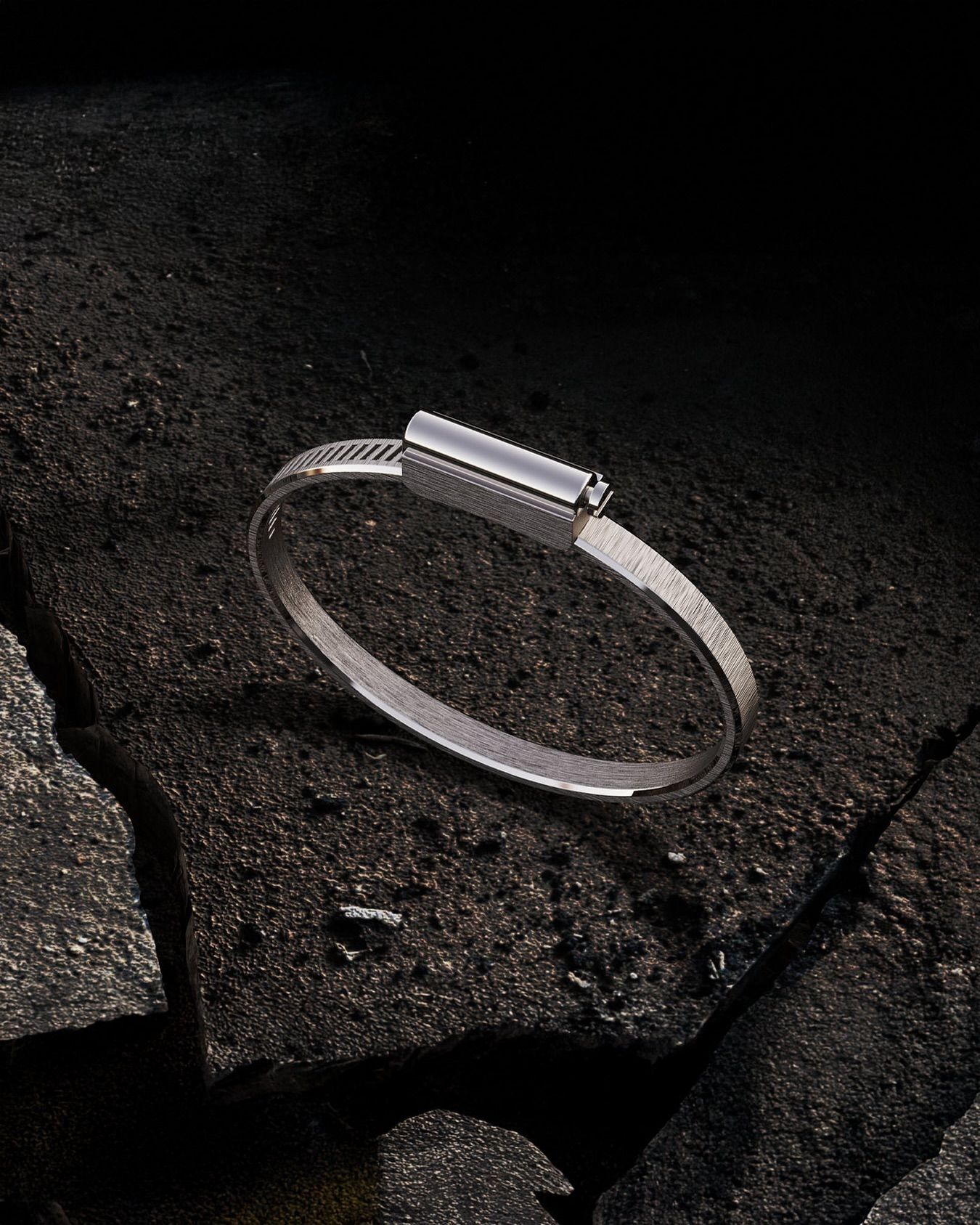 Bracelet en argent sur une surface sombre et texturée.