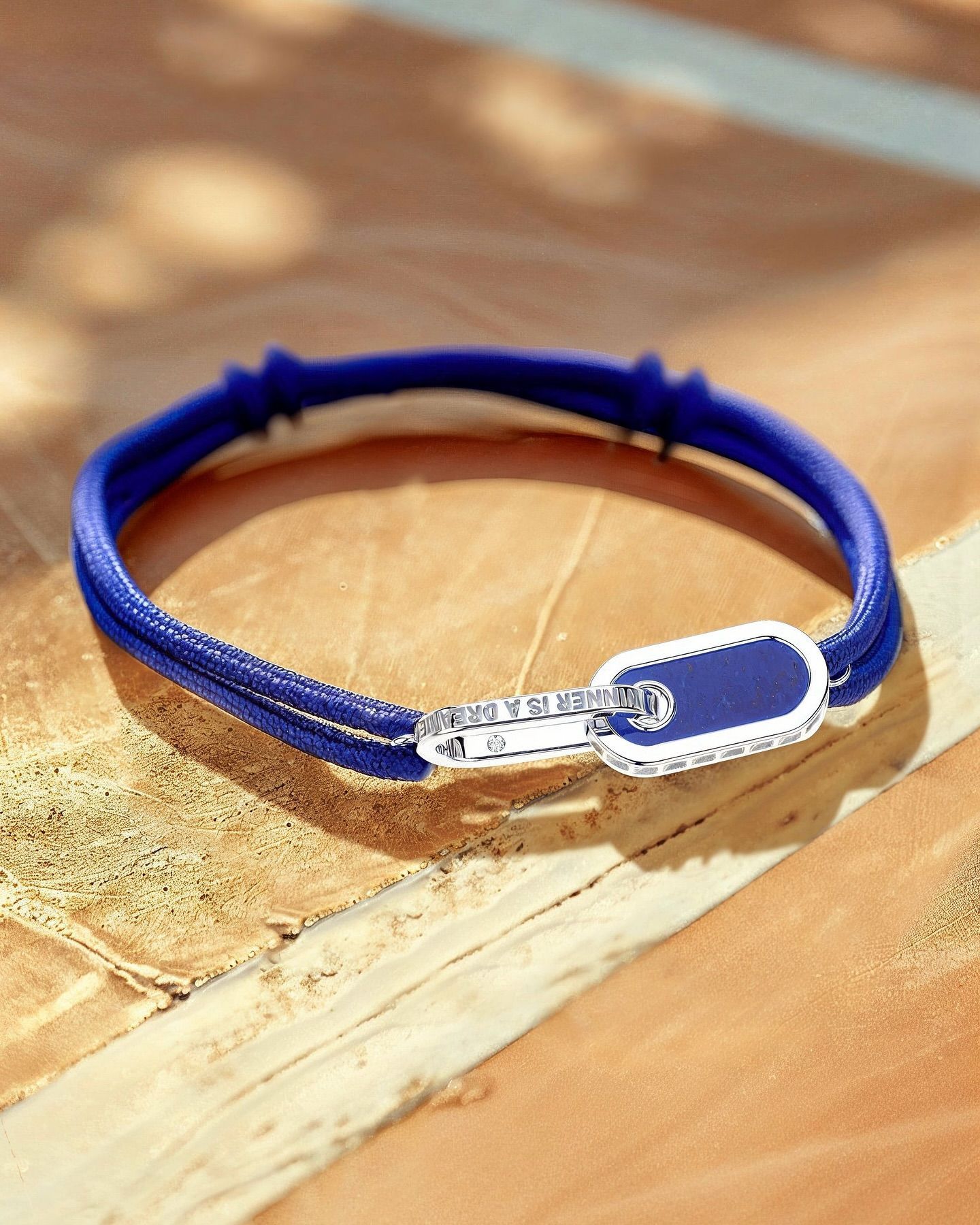 Bracelet bleu avec fermoir diamant sur une surface en bois.