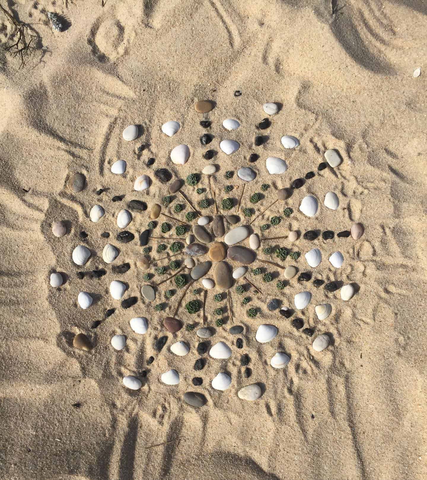 Mandala de pierre et de coquillage sur sable.
