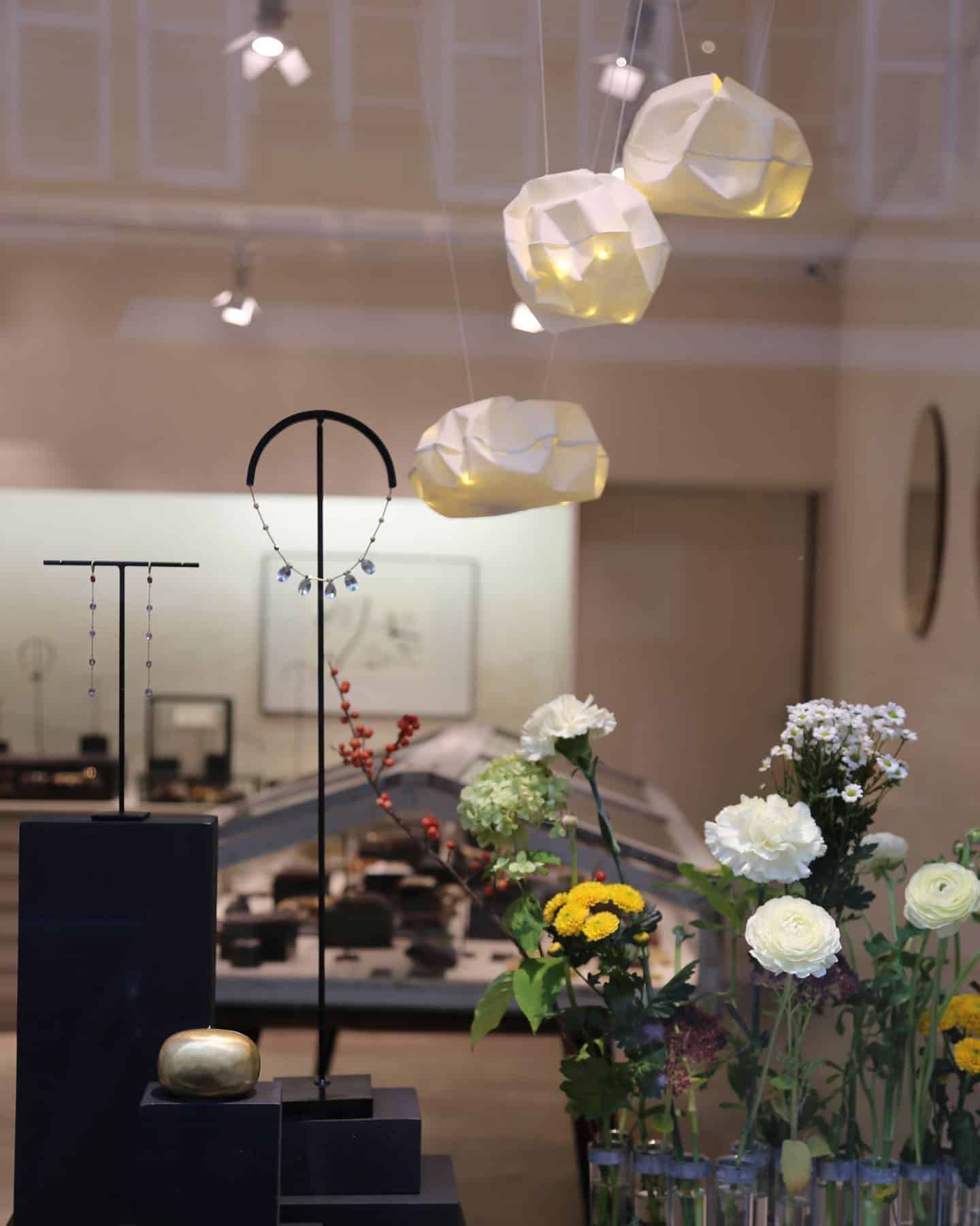 Présentoir de bijouterie. Présentoirs noirs avec colliers, compositions florales et suspensions géométriques.