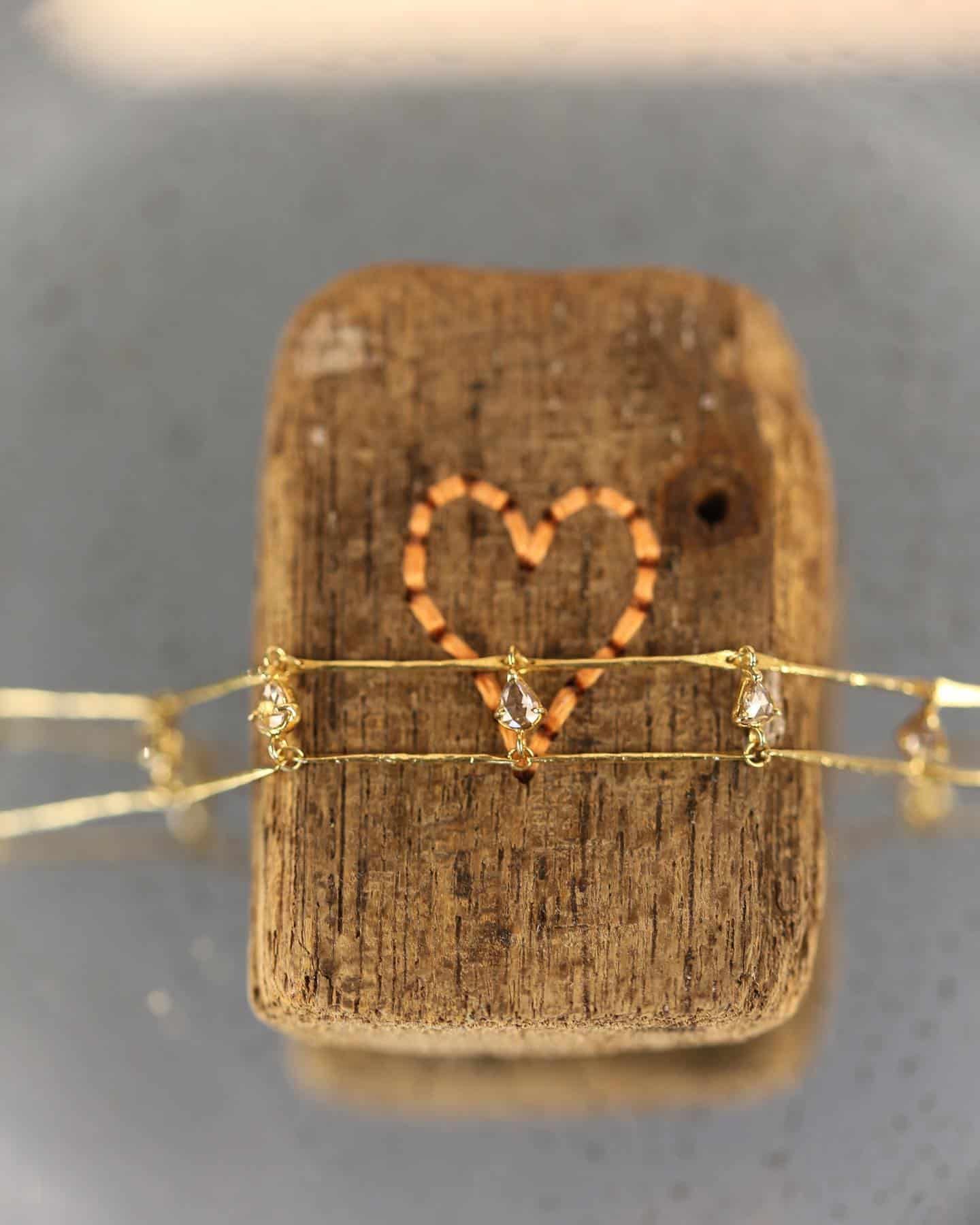 Collier en or avec petits diamants sur un bloc de bois avec un coeur orange.