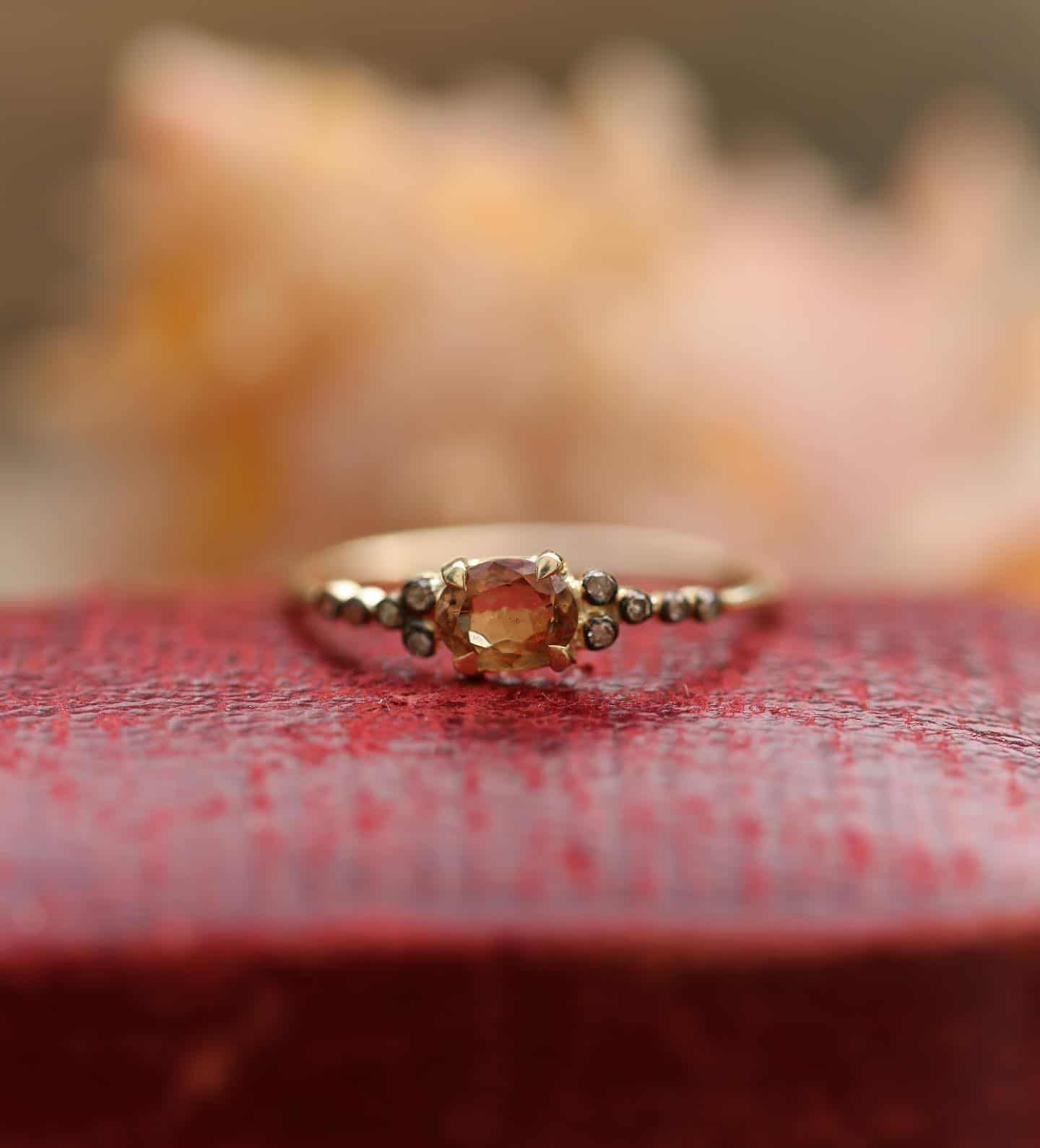 Bague en or avec une pierre jaune carrée, sertie de petites pierres blanches le long de la bande.