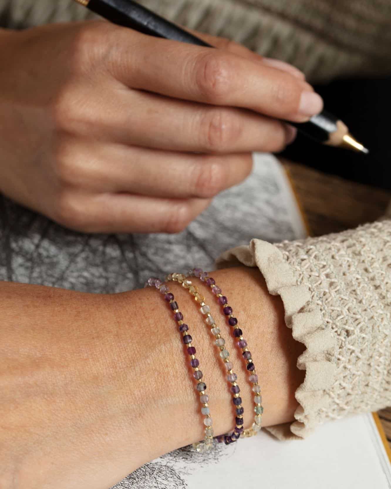 Dessin d'une personne au crayon ; poignet avec trois bracelets de perles colorées.