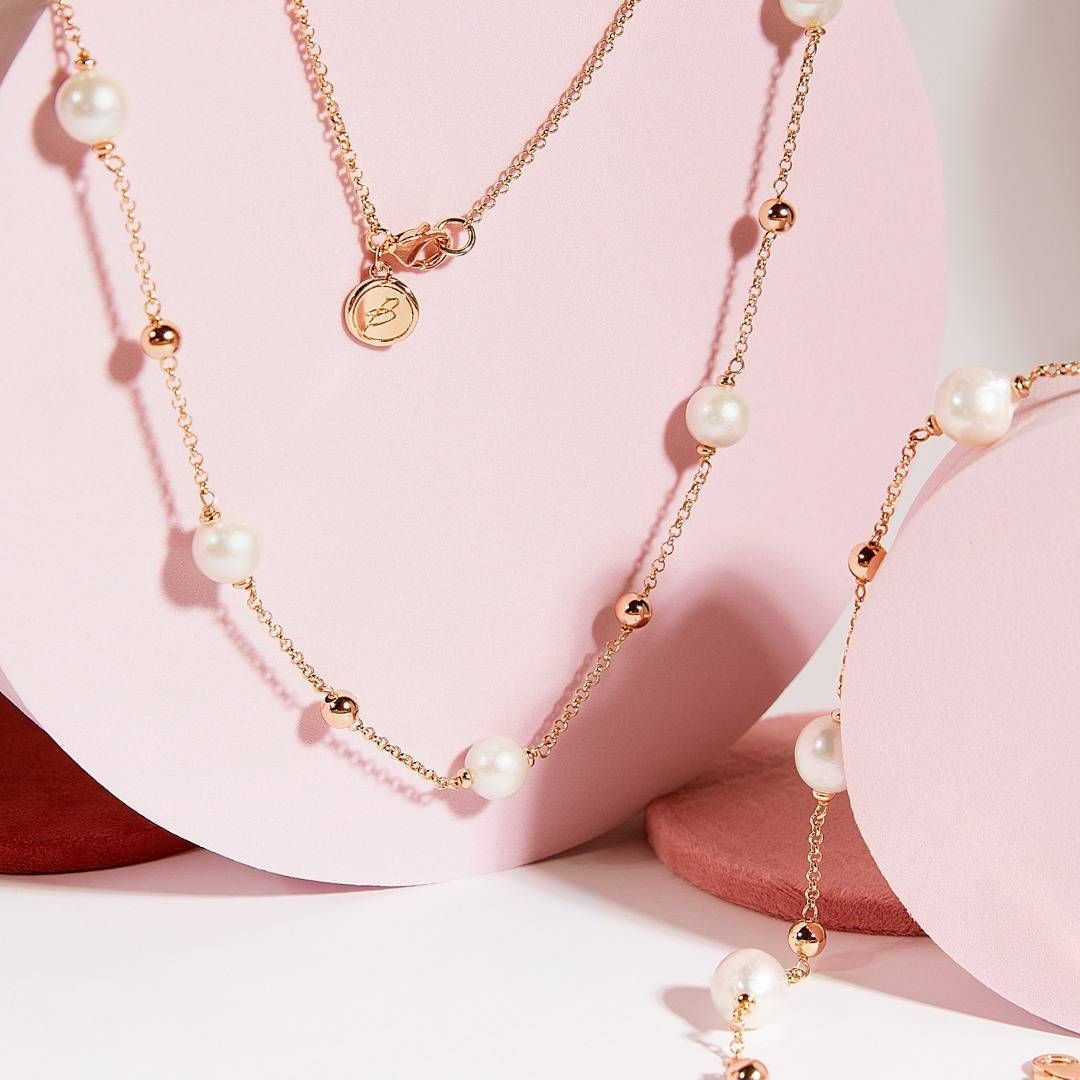 Collier en or rose avec perles et petites perles d'or sur fond rose.