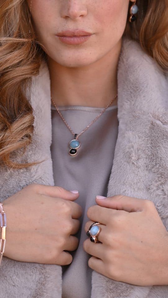 Femme portant des bijoux en pierres précieuses bleues et un manteau de fourrure, les mains jointes.