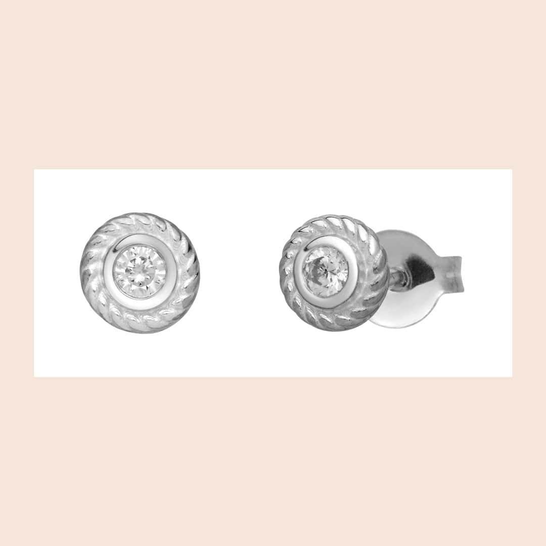 Boucles d'oreilles à tige en argent avec un design circulaire et une pierre centrale.