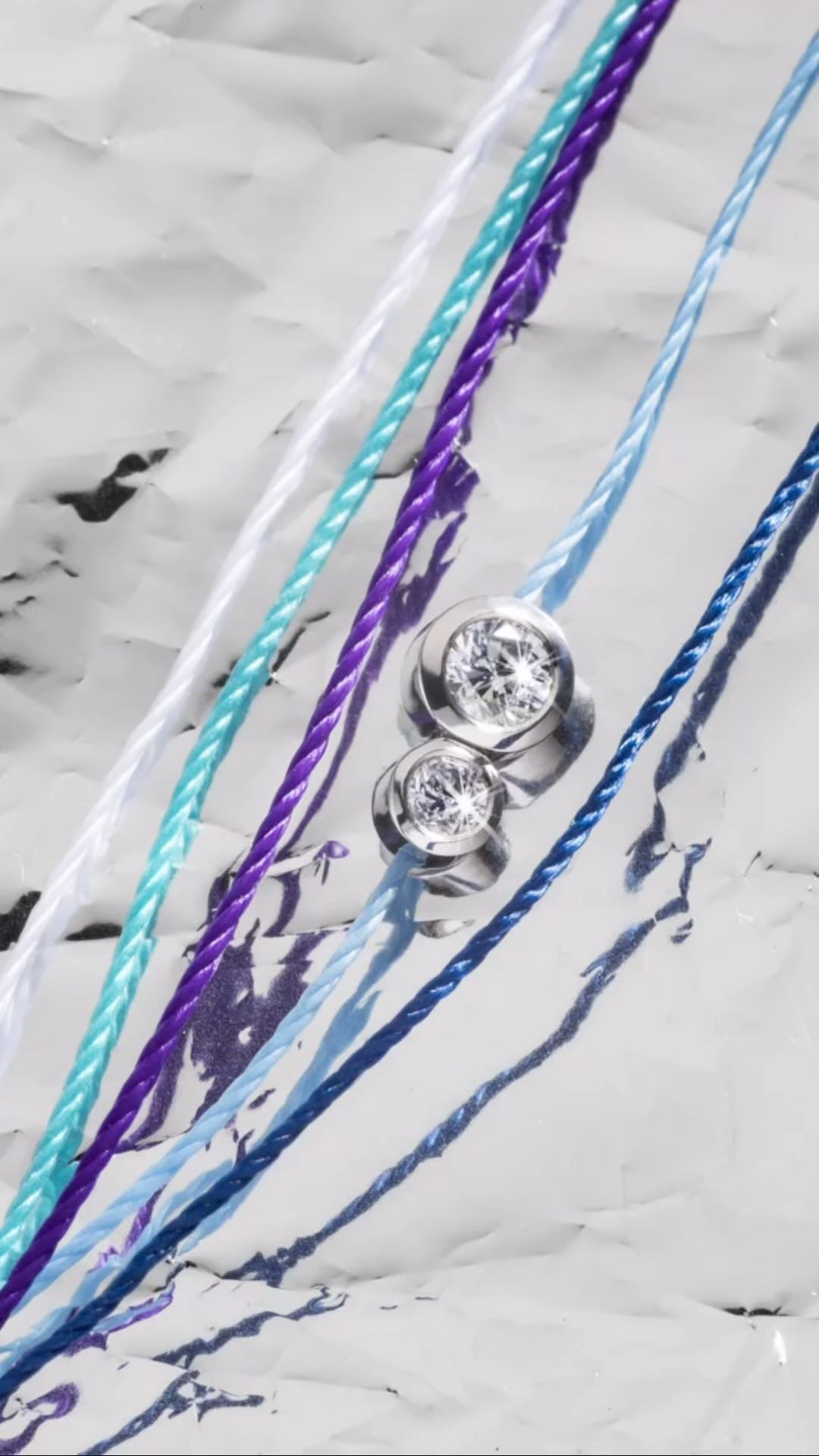 Pendentifs en diamant sur des bracelets en corde colorés, disposés sur du papier blanc texturé.