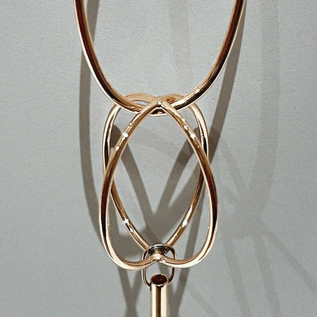 Bijou abstrait couleur or. Deux créoles supérieures sont reliées à un motif inférieur en forme de cœur orné d'un petit pendentif.