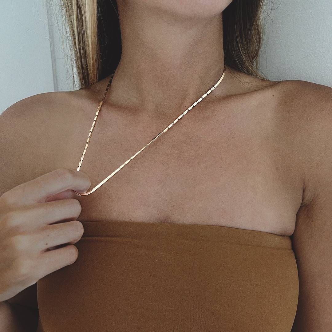 Femme portant un collier en chaîne en or et un haut tube marron.