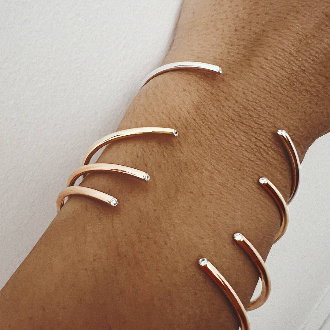 Bracelet manchette en or rose sur un poignet.