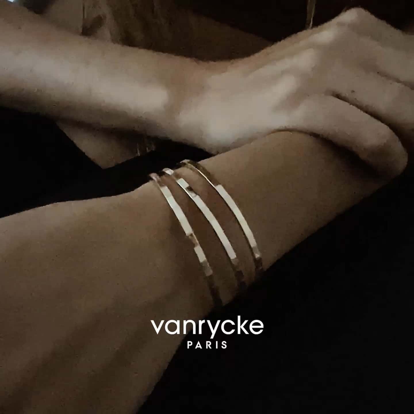 Personne portant plusieurs bracelets en or avec le logo