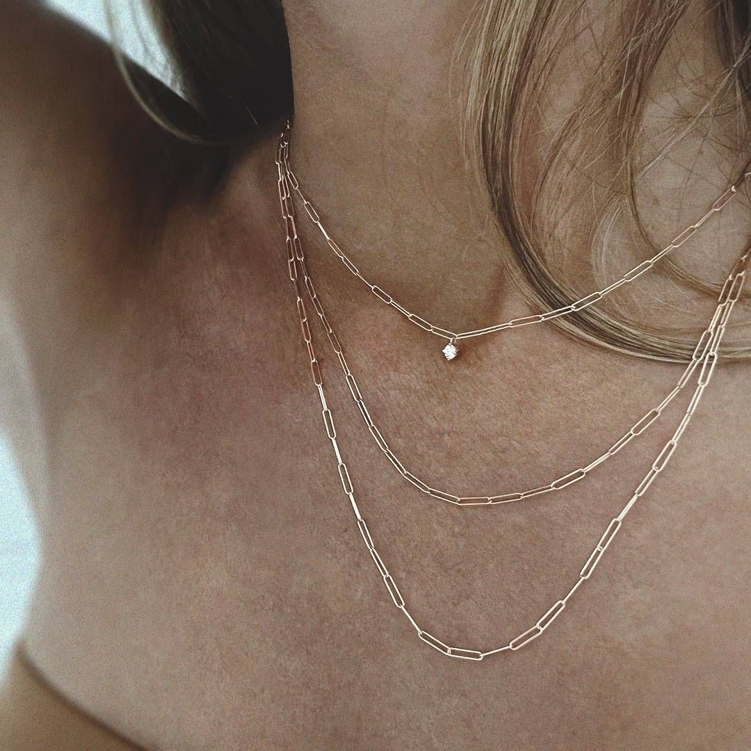 Femme portant trois colliers en or superposés.