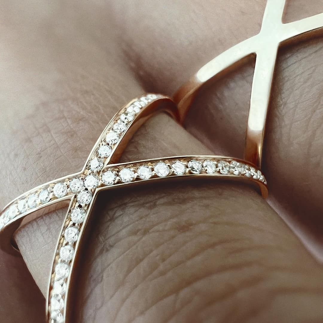 Gros plan de deux bagues croisées en or rose, dont une avec des diamants, sur le doigt d'une personne.