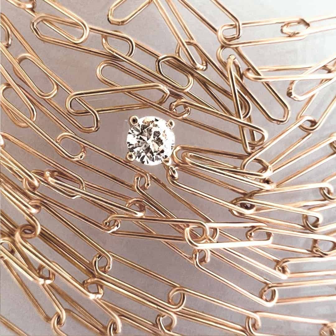 Bague en diamant centrée dans une pile de trombones en or.