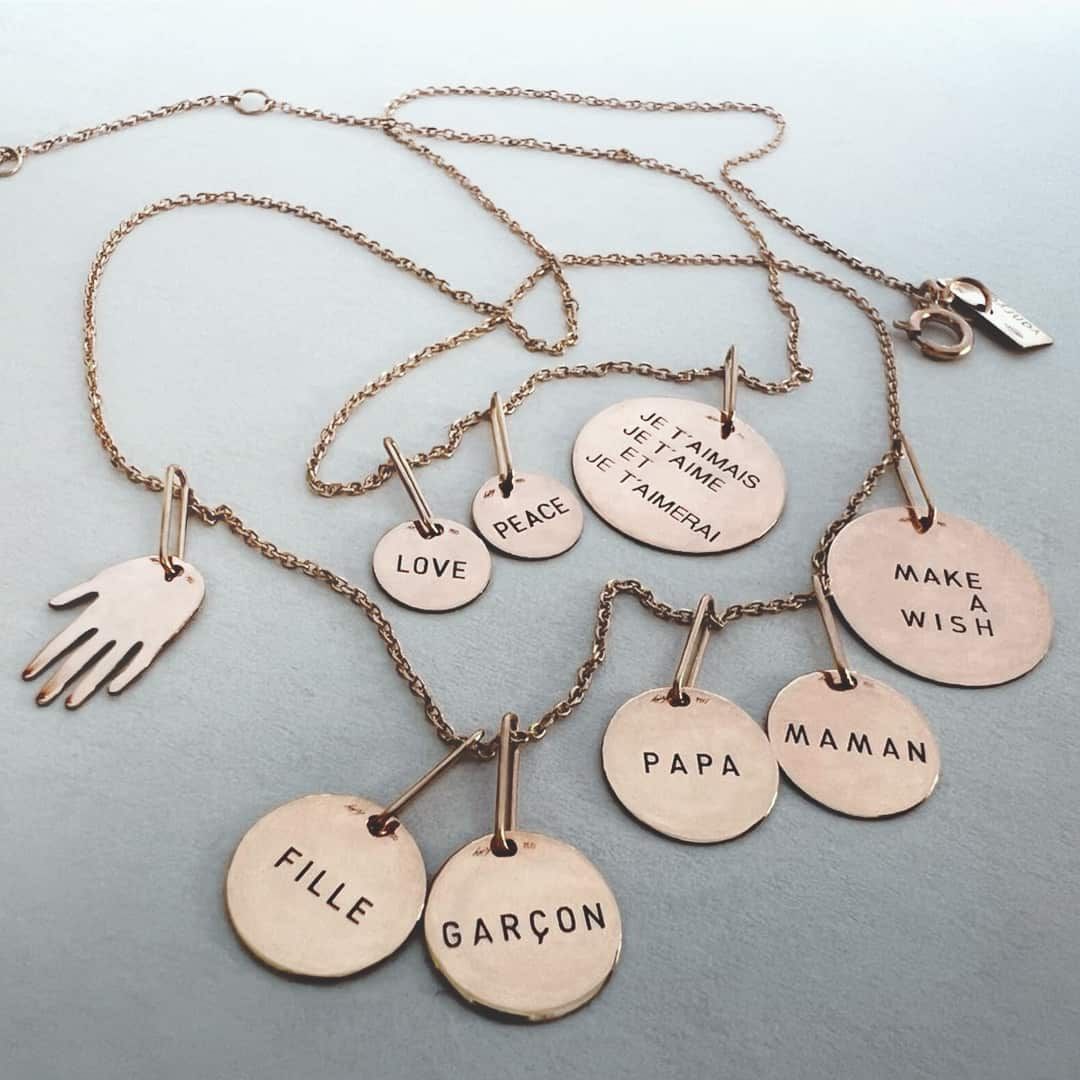 Colliers en or avec pendentifs portant des mots comme « AMOUR », « PAIX » et « FAITES UN VŒU ».