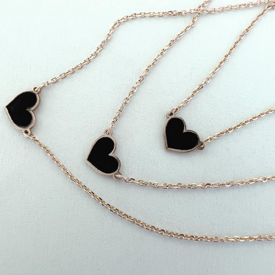 Colliers en or rose avec pendentifs en forme de cœur noir.