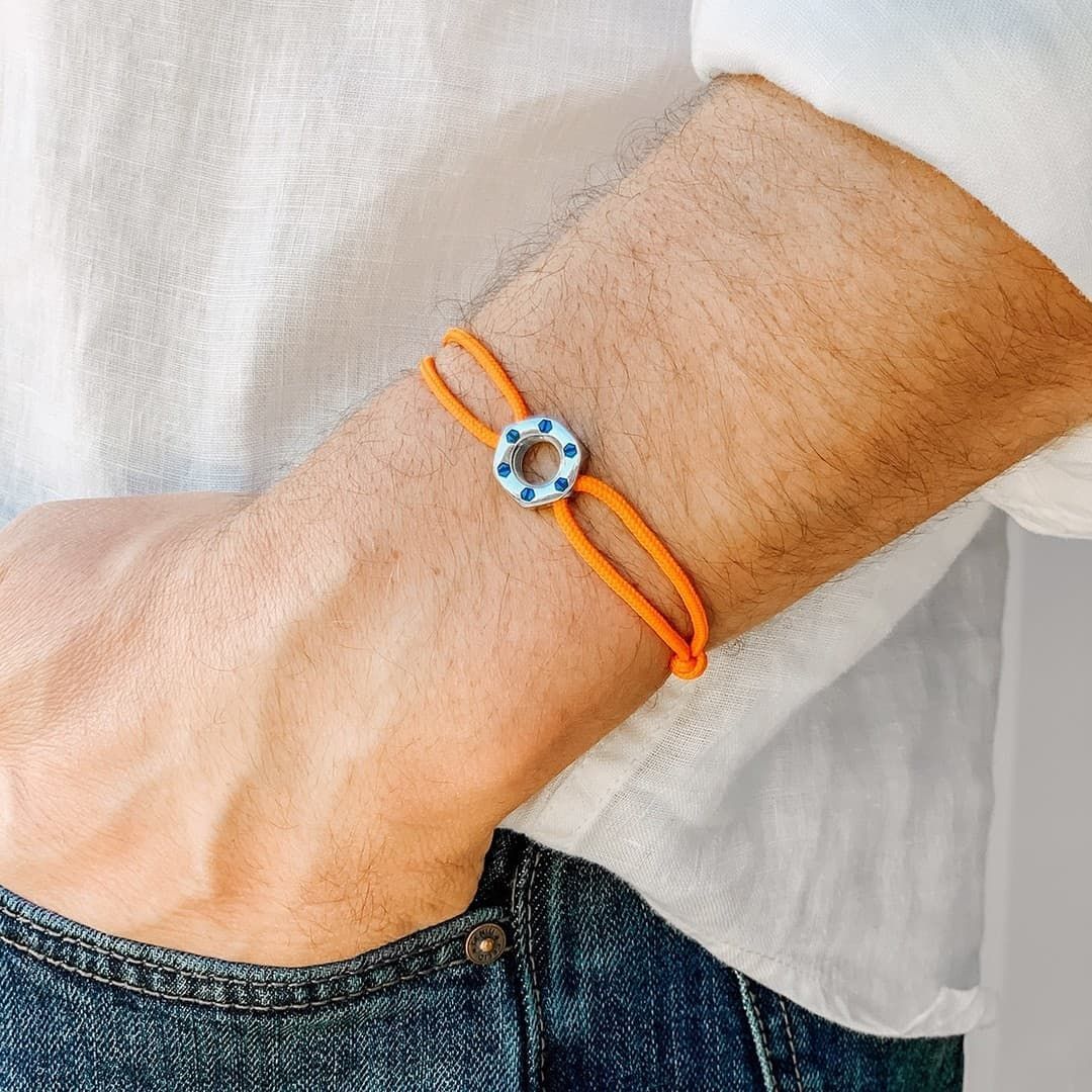 Homme portant un bracelet orange vif avec une pièce centrale circulaire bleue et blanche.