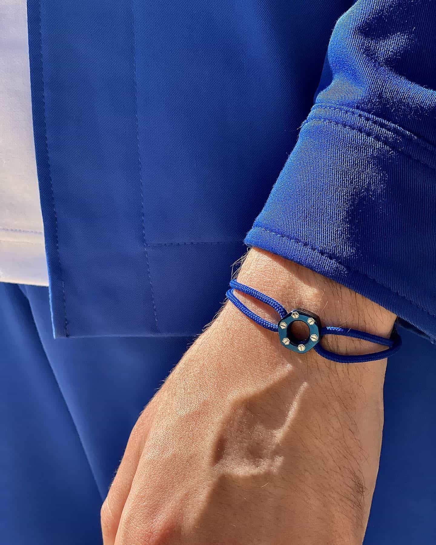 Poignet d'une personne avec un bracelet bleu, portant une veste et un pantalon bleus.
