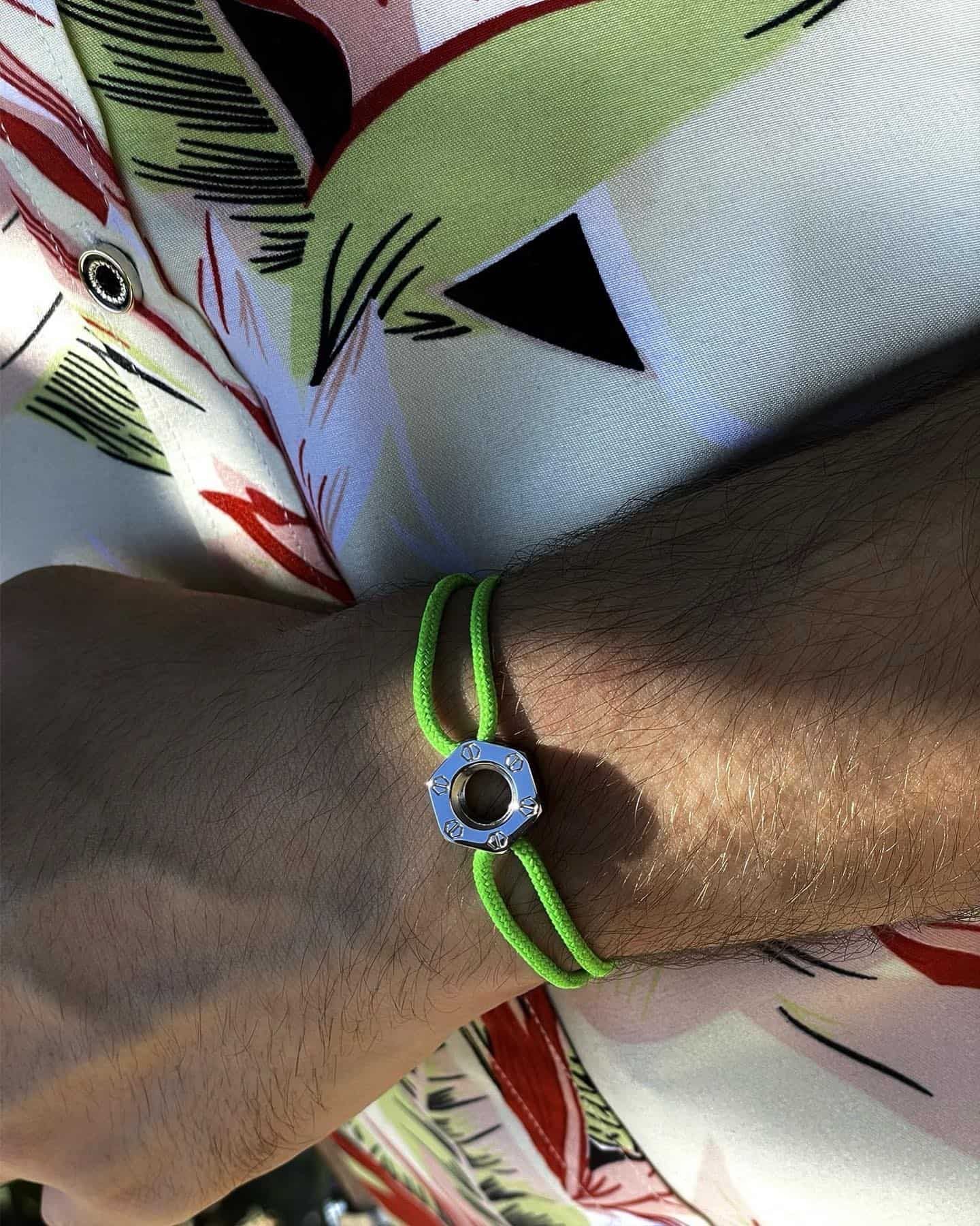 Une personne portant un bracelet vert vif avec une pièce centrale en argent sur son poignet.