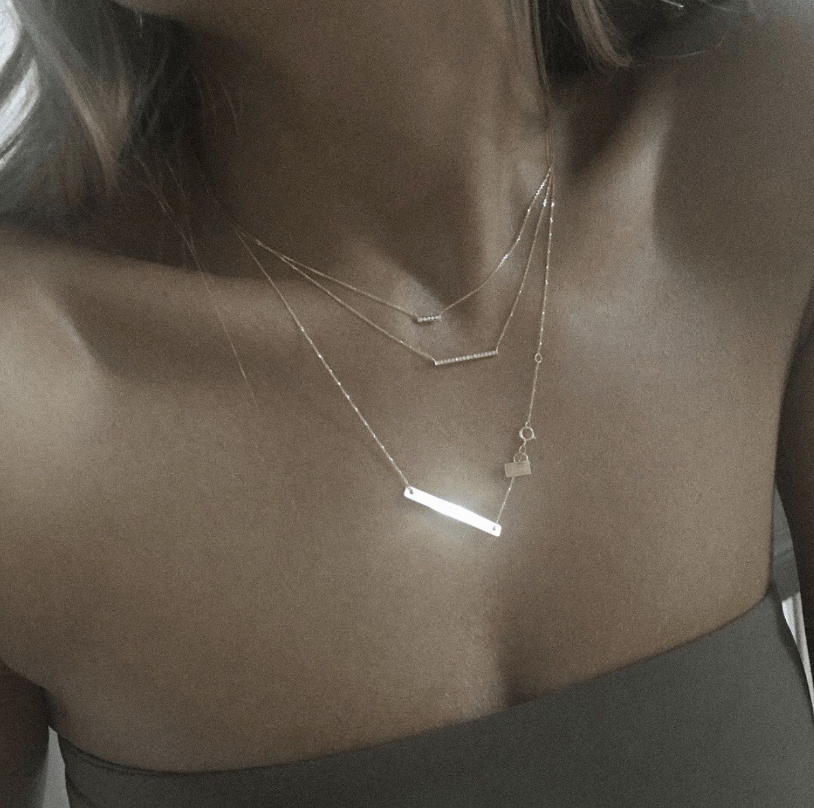 Femme portant trois colliers en or superposés, gros plan.