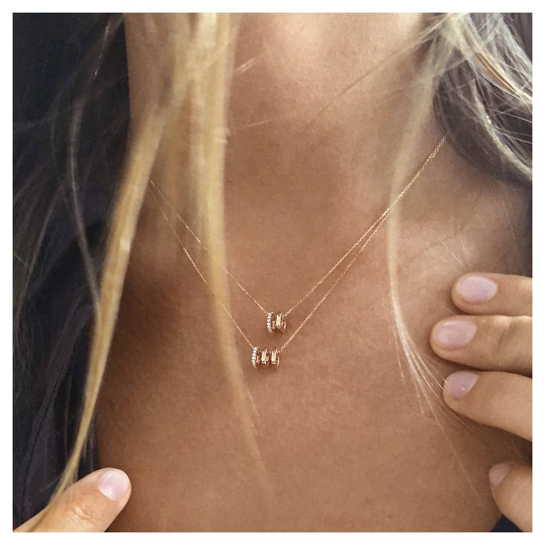Femme portant deux délicats colliers en or avec de petits pendentifs.