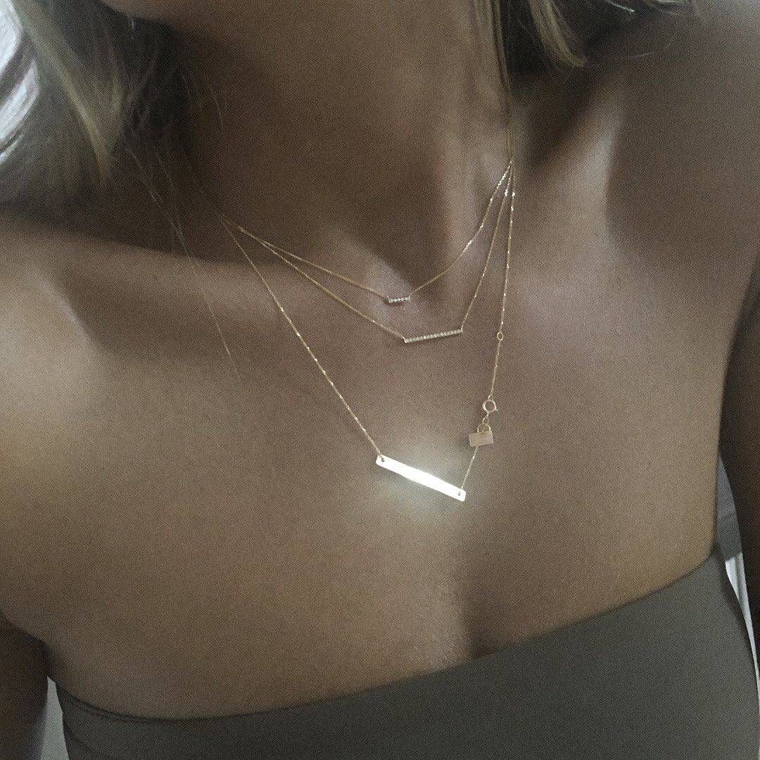 Femme portant trois colliers en or superposés et un haut bustier beige.