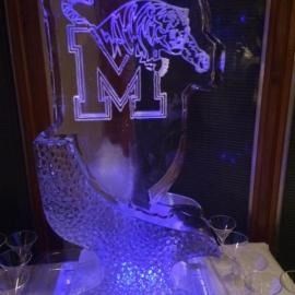 Lit purple crystal tiger sculpture in front of a mirrored Memphis “M” logo