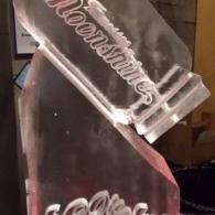 Clear acrylic display with etched cursive lettering, shown at an angle against a dark background.