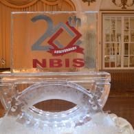 Clear ice sculptured plaque with “25th Anniversary NBIS” in red and blue on a decorative stand.