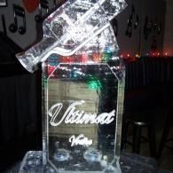 Clear acrylic bottle-shaped trophy with white script on a dark table in a dim room