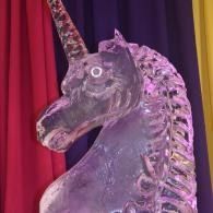 Decorative unicorn head ice sculpture lit in purple against red and black drapes